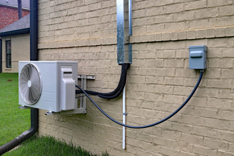 Air Conditioner mini split system next to home with brick wall