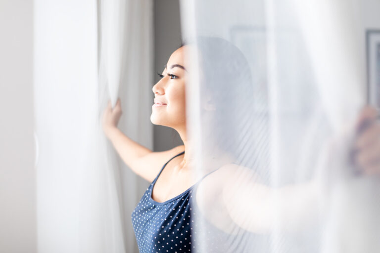 Smiling woman opening curtains