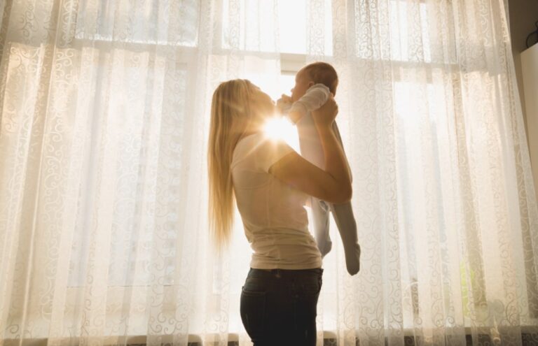 A mother and baby dancing with sunshine pouring through the window behind them